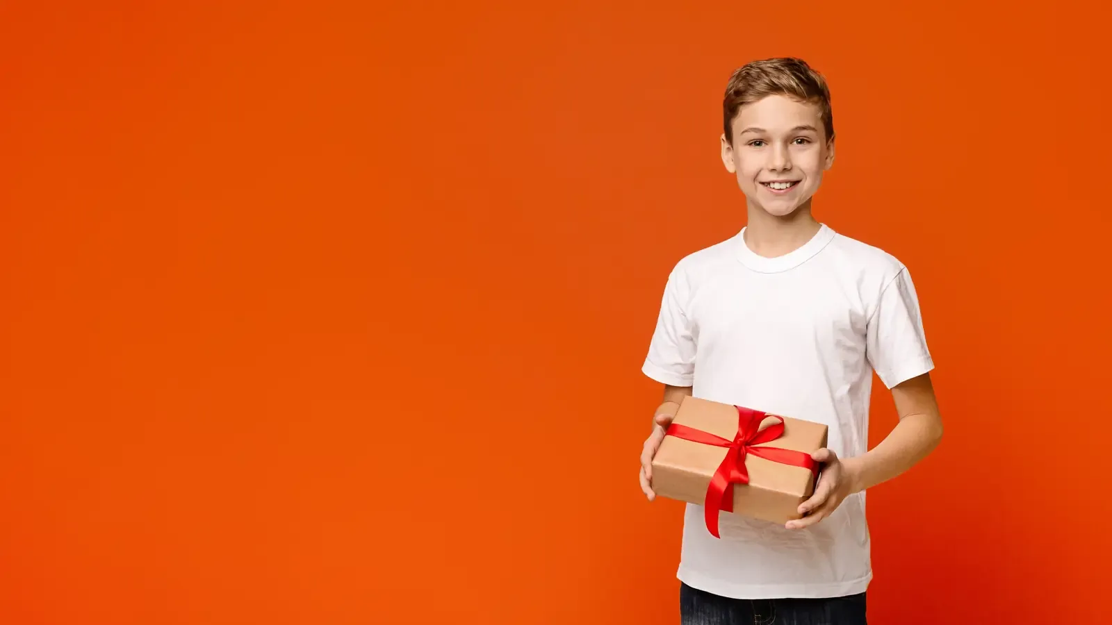 A smiling teenage boy holding a wrapped holiday gift box